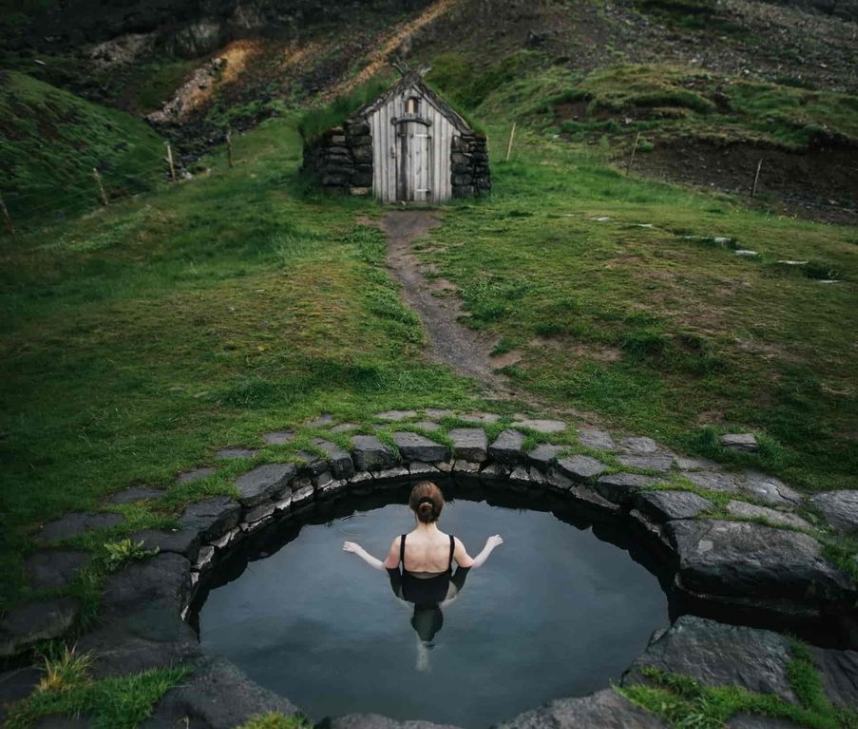 Guðrúnarlaug historic stone hot spring pool beside turf hut in West Iceland Guðrúnarlaug historic stone hot spring pool beside turf hut in West Iceland